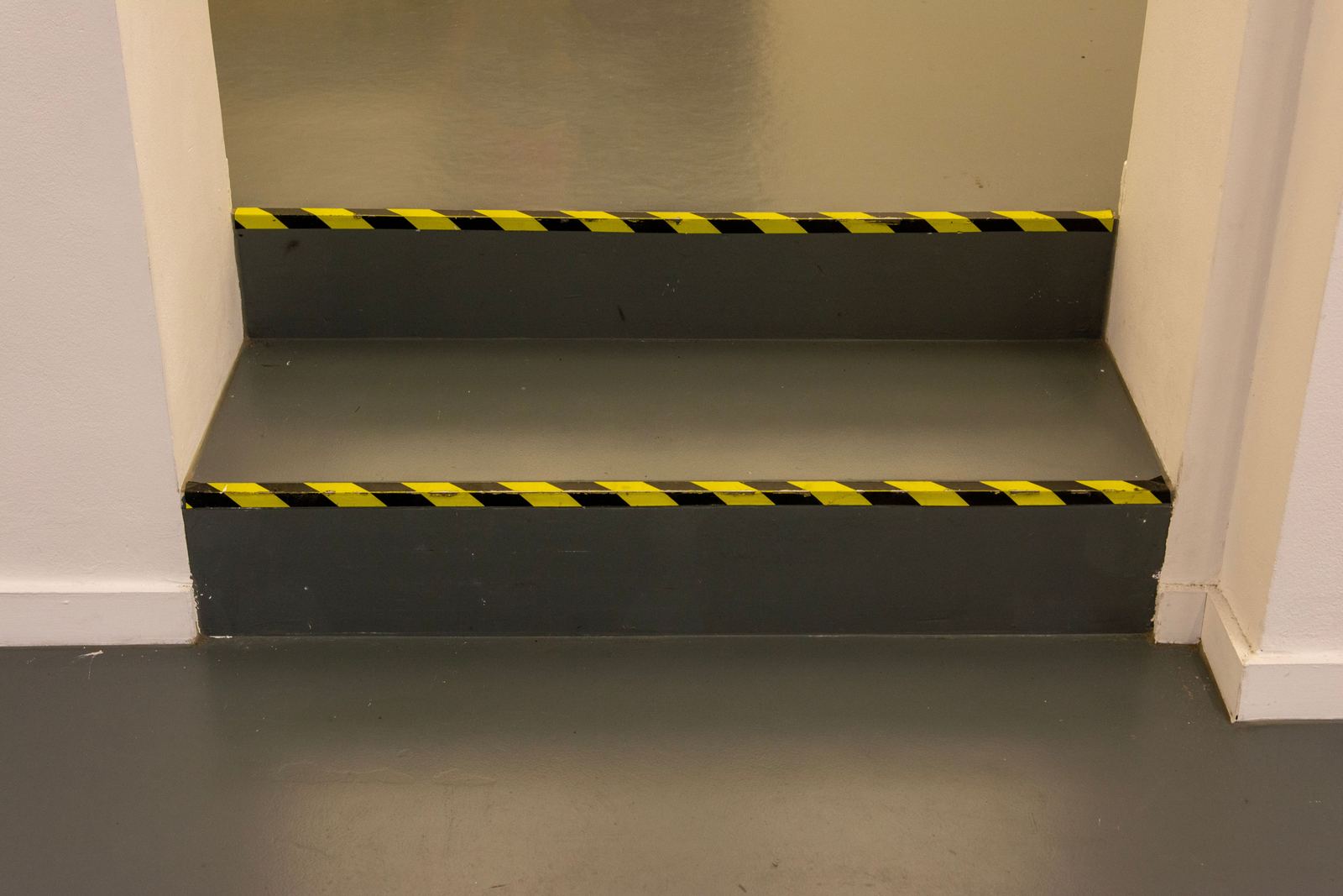 Twee traptreden met zwart-gele markeringstape op de neus van elke trede